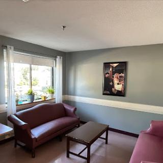 A cozy living room featuring two red couches, a coffee table, and bright natural light coming through the window.