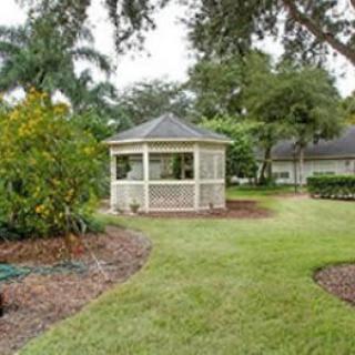 A scenic garden featuring a charming gazebo surrounded by lush greenery and trees.