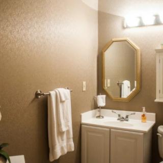 A well-lit bathroom featuring a sink with a mirror, towel rack, and decorative wallpaper.