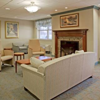A cozy living room with comfortable seating and a fireplace, adorned with artwork.