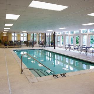 An indoor swimming pool with surrounding seating and large windows.