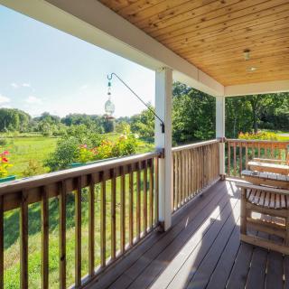 A sunny porch overlooking a lush green landscape.