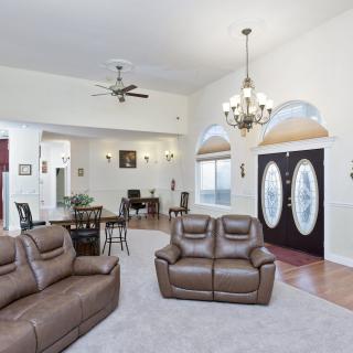 Spacious living room with elegant furnishings, featuring a chandelier, ceiling fan, and arched windows.