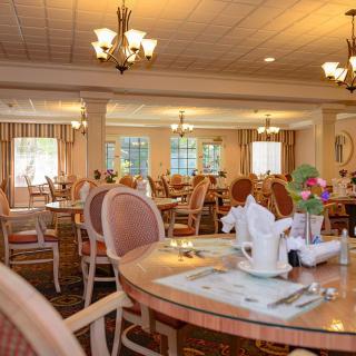 An elegant dining room with neatly set tables and chandeliers.