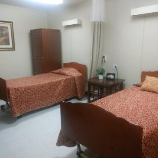 A shared hospital room featuring two beds with brown frames and patterned blankets.
