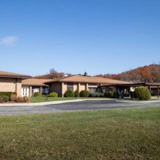 A single-story building with a flat roof, surrounded by grass and set against a clear blue sky.