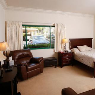 A cozy bedroom with a bed, leather chair, and window view.