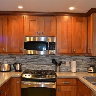 A modern kitchen with wood cabinets, stainless steel appliances, and a stylish backsplash.
