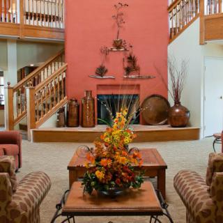 A cozy living room featuring a central fireplace, autumn-themed decorations, and comfortable seating.
