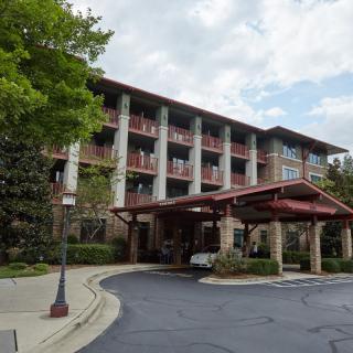A hotel building with a grand entrance surrounded by trees under a cloudy sky.