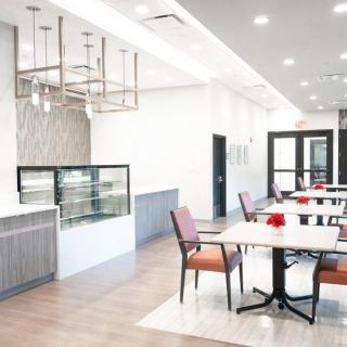 A modern, minimalist cafe interior with several empty tables and chairs.