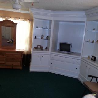 A cozy living room with built-in white shelves and a small television.