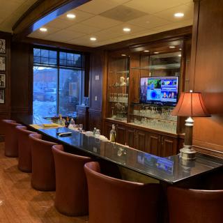 A modern bar interior with a sleek counter, comfortable seating, and a wall-mounted television.