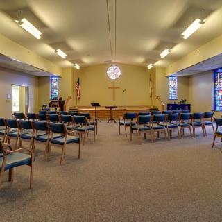 An interior view of a chapel with arranged seating and a central pulpit.