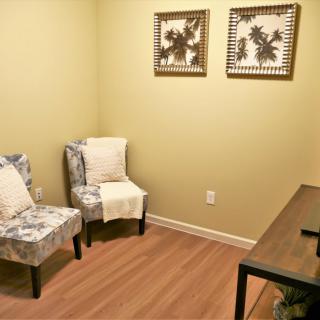 A minimalist office space with chairs, a desk, and framed artwork.