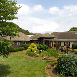 A single-story house with a well-maintained garden and lawn on a cloudy day.