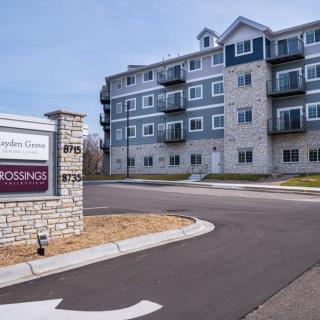 A modern apartment complex with a prominent entrance sign in an urban setting.