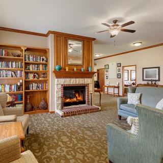 A cozy living room with a fireplace and bookshelves, featuring comfortable seating and warm decor.