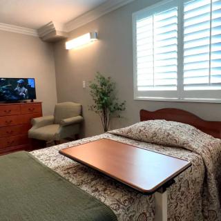 A hospital room with a bed, television, and chair.