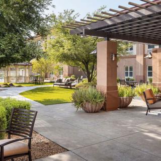 A sunny outdoor patio area featuring comfortable seating and lush greenery.