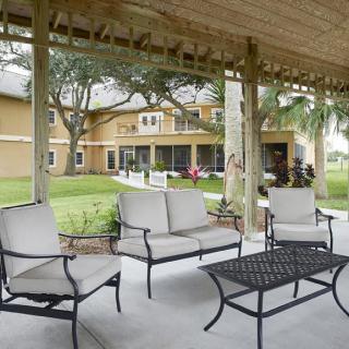 A cozy patio area with outdoor furniture overlooking a spacious backyard and house.