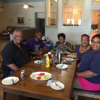 A family enjoying a meal together at a dining table with smiles.