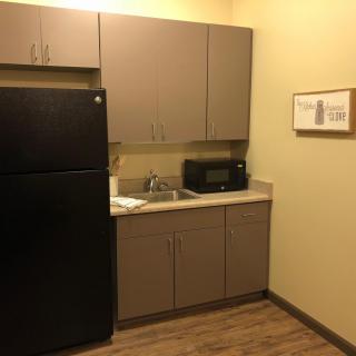 A compact kitchen area with a refrigerator, cabinets, microwave, and sink.