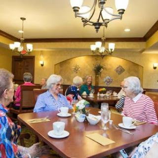 Seniors enjoying a social gathering over tea in a warm and inviting dining area.