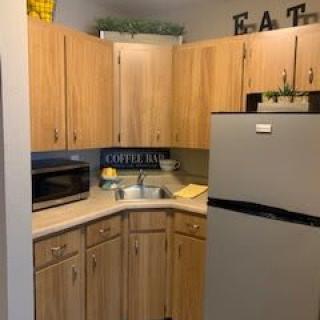 A cozy kitchen corner with wooden cabinets, a silver refrigerator, and a microwave on the countertop.
