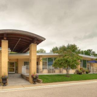 A contemporary building with a welcoming entrance, set against a cloudy sky.