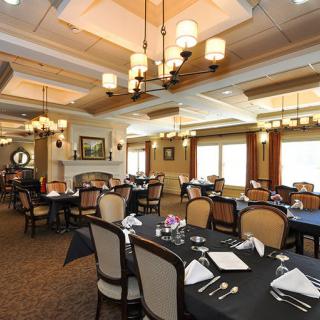An elegant dining room with neatly arranged tables and chandeliers.