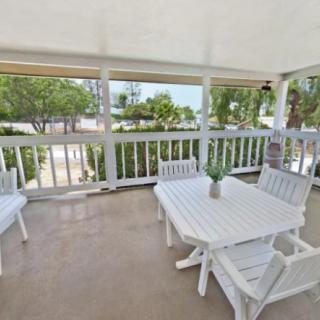 A cozy outdoor porch with white furniture overlooking lush greenery.