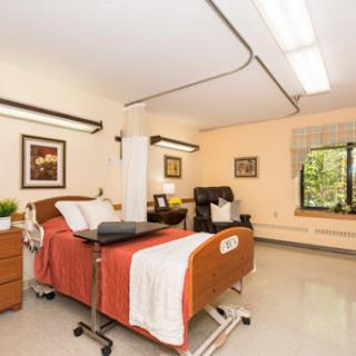 A cozy patient room equipped with essential healthcare furniture and ample natural light.