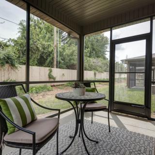 Cozy screened-in porch with a garden view, featuring a small table and chairs for relaxation.