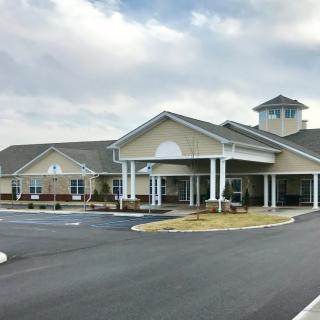 A large, modern building with a spacious parking lot under a cloudy sky.