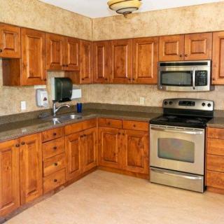 A kitchen with wooden cabinets and stainless steel appliances, featuring a corner layout.
