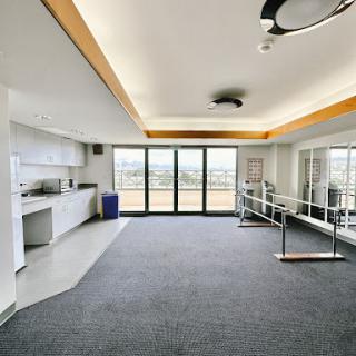 A spacious and modern office room featuring a kitchenette and large windows that provide ample natural light.