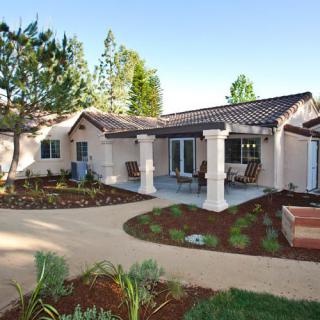 A beautifully landscaped front yard featuring a modern house with a patio and garden.