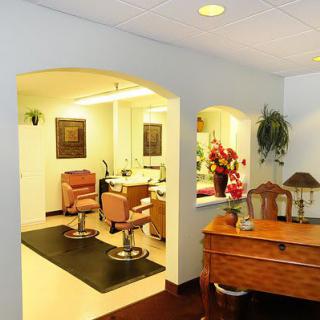 A well-lit salon interior with styling chairs and a reception desk adorned with flowers.
