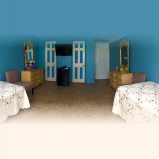A hotel room featuring two beds, wooden furniture with mirrors, and a flat-screen TV mounted on the wall.