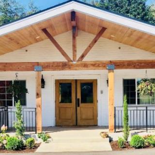 A charming house with a wooden front entrance and well-maintained landscaping on a sunny day.