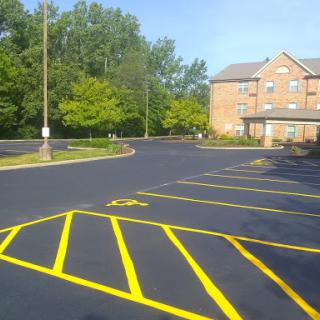 A well-maintained parking lot with freshly painted yellow lines adjacent to a building surrounded by greenery.