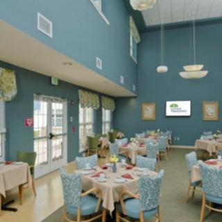 A spacious dining room with blue walls, elegantly set tables, and large windows letting in natural light.