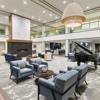 A spacious and elegantly designed lounge with comfortable seating, a fireplace, and a grand piano.
