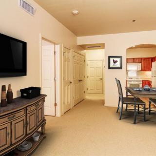 A cozy living and dining area with a view into the kitchen, featuring modern furniture and decor.