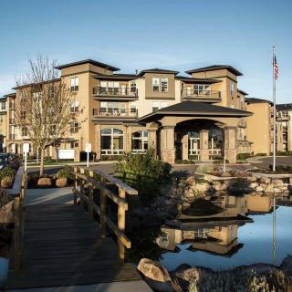 A modern residential building with landscaped surroundings and a reflective pond.