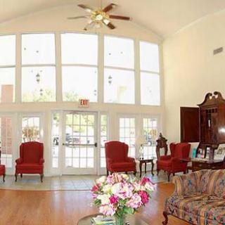 A spacious and bright living room with large windows, elegant furniture, and a floral arrangement on the table.