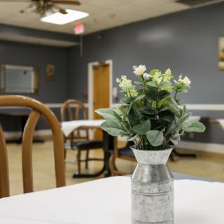 A cozy dining area featuring a simple table with a decorative plant in a vase.