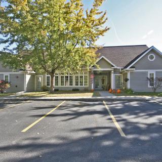 A building surrounded by trees and a parking lot in autumn sunlight.