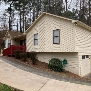A single-story house with a red front porch, surrounded by trees and featuring a driveway.